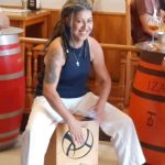 a woman with dreads sitting on a wine barrel